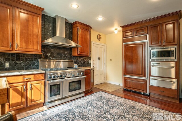 182 Mill St, Genoa, NV 89411 - kitchen featuring built in appliances, wall chimney range hood, a warming drawer, backsplash, and light wood-style floors