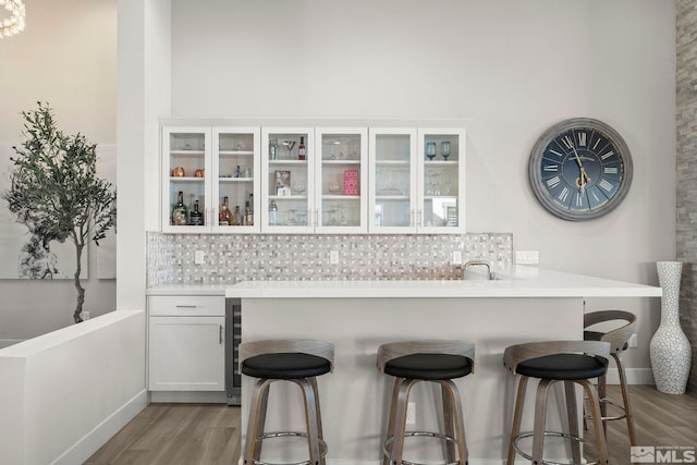 kitchen with a breakfast bar area, light wood-style floors, and backsplash