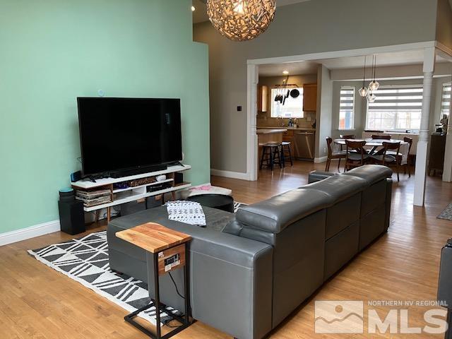 living area with a chandelier, baseboards, and light wood finished floors