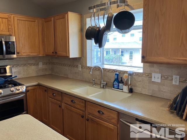 kitchen with appliances with stainless steel finishes, a sink, and backsplash
