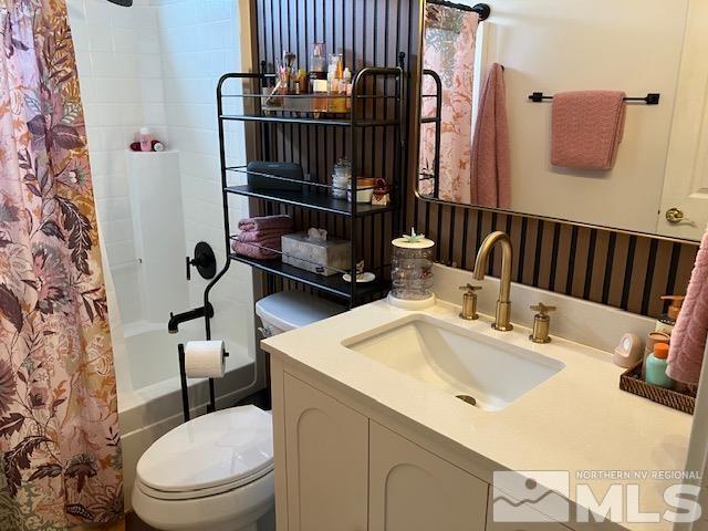 bathroom featuring toilet, shower / bath combination with curtain, and vanity
