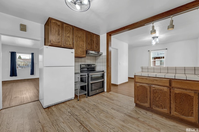 435 14th St, Sparks, NV 89431 - kitchen with freestanding refrigerator, range with two ovens, tile countertops, under cabinet range hood, and light wood-style floors
