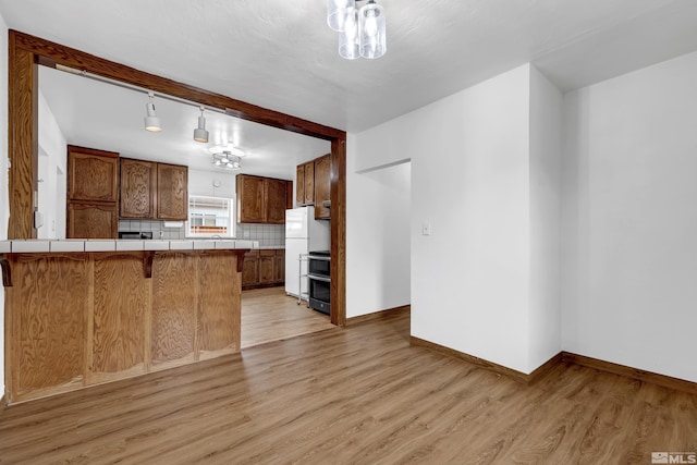 435 14th St, Sparks, NV 89431 - kitchen featuring tile countertops, a kitchen breakfast bar, freestanding refrigerator, light wood-type flooring, and tasteful backsplash