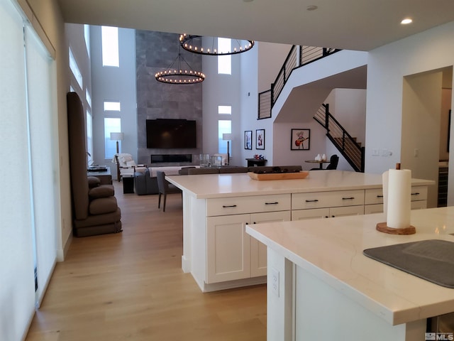5449 Side Saddle Trl, Reno, NV 89511 - kitchen featuring a center island, light wood finished floors, white cabinets, a high ceiling, and a chandelier