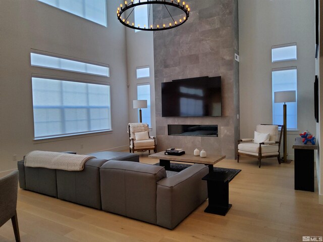 5449 Side Saddle Trl, Reno, NV 89511 - living room featuring a towering ceiling, a tiled fireplace, wood finished floors, and a chandelier