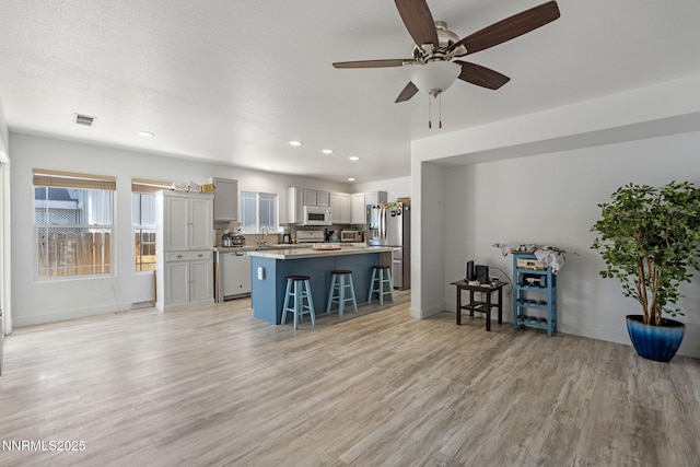 7721 Welsh Dr, Reno, NV 89506 - kitchen featuring dishwashing machine, white microwave, a breakfast bar area, a center island, and stainless steel fridge