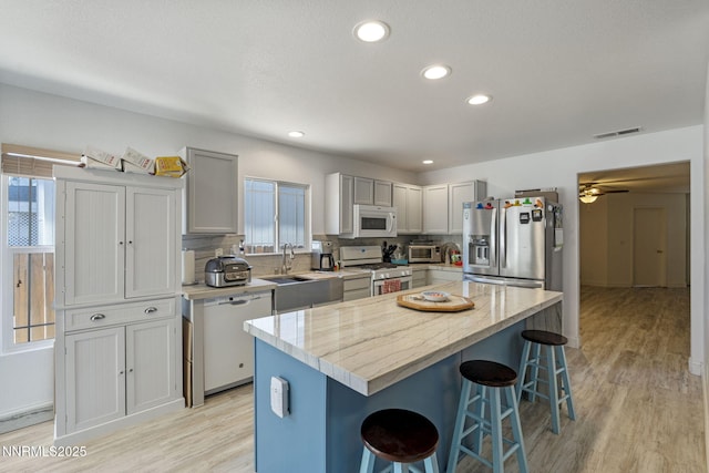 7721 Welsh Dr, Reno, NV 89506 - kitchen featuring white appliances, a breakfast bar, light wood-style flooring, decorative backsplash, and recessed lighting