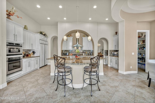 10100 Via Ponte, Reno, NV 89511 - kitchen with arched walkways, stainless steel double oven, tasteful backsplash, a large island, and recessed lighting
