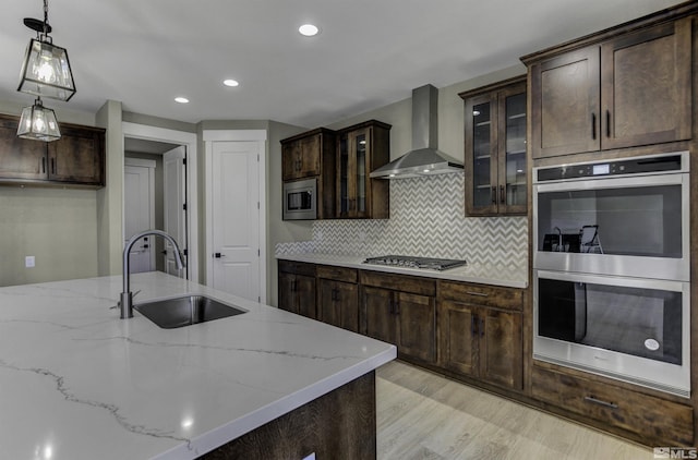 1791 La Cita, Minden, NV 89423 - kitchen with wall chimney range hood, a sink, stainless steel appliances, dark brown cabinetry, and hanging light fixtures