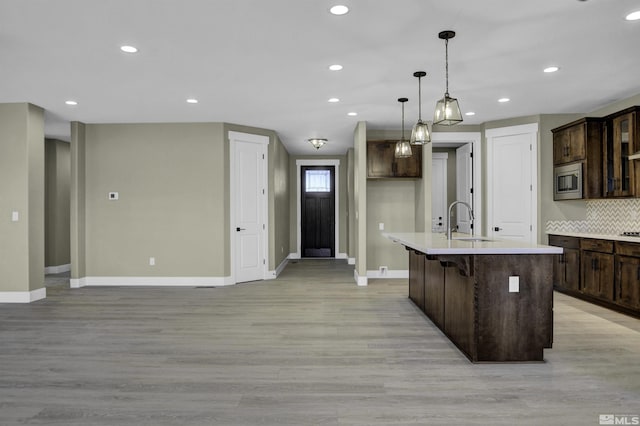 1791 La Cita, Minden, NV 89423 - kitchen featuring stainless steel microwave, baseboards, light wood-style flooring, a sink, and dark brown cabinets