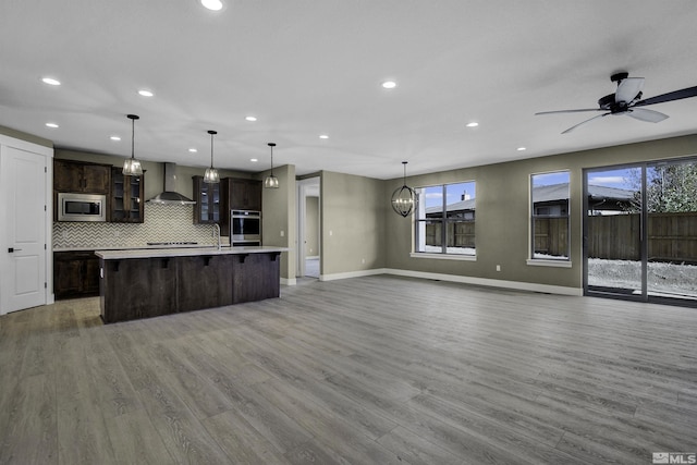 1791 La Cita, Minden, NV 89423 - kitchen with stainless steel microwave, wall chimney range hood, open floor plan, dark brown cabinetry, and recessed lighting