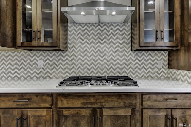 1791 La Cita, Minden, NV 89423 - kitchen featuring wall chimney exhaust hood, dark brown cabinets, stainless steel gas stovetop, light countertops, and glass insert cabinets