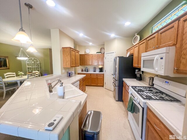 1090 Aster Ln, Fernley, NV 89408 - kitchen featuring white appliances, tile counters, a sink, decorative light fixtures, and brown cabinets