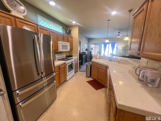 1090 Aster Ln, Fernley, NV 89408 - kitchen with white appliances, tile countertops, brown cabinetry, and recessed lighting