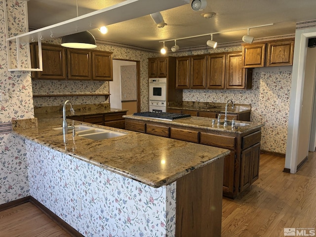 3 Comstock Cir, Carson City, NV 89703 - kitchen with wallpapered walls, a sink, light wood finished floors, an island with sink, and gas cooktop