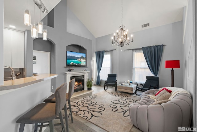 17000 Wedge Pkwy Unit 3221, Reno, NV 89511 - living room with a chandelier, light wood-style flooring, a warm lit fireplace, and high vaulted ceiling