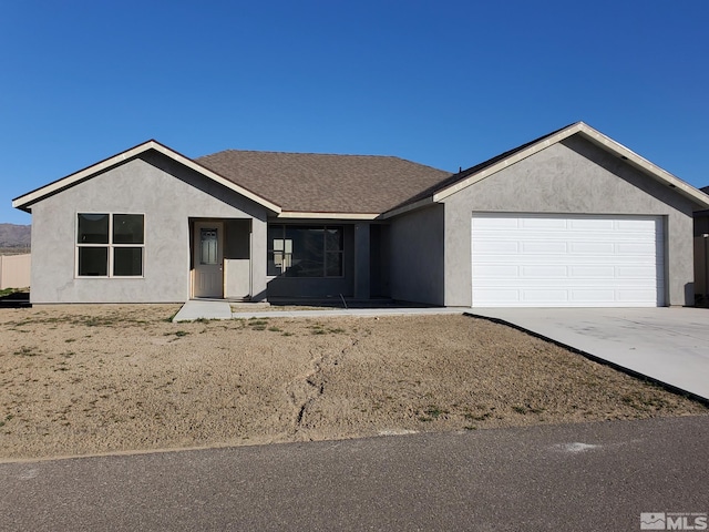 ranch-style home featuring a garage, concrete driveway, stucco siding, and roof with shingles