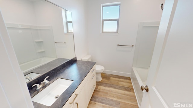 bathroom with vanity, wood finished floors, toilet, baseboards, and tub / shower combination