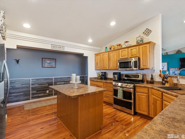 4259 Rancheria Rd, Fallon, NV 89406 - kitchen with stainless steel appliances, a sink, vaulted ceiling, light wood finished floors, and a kitchen island