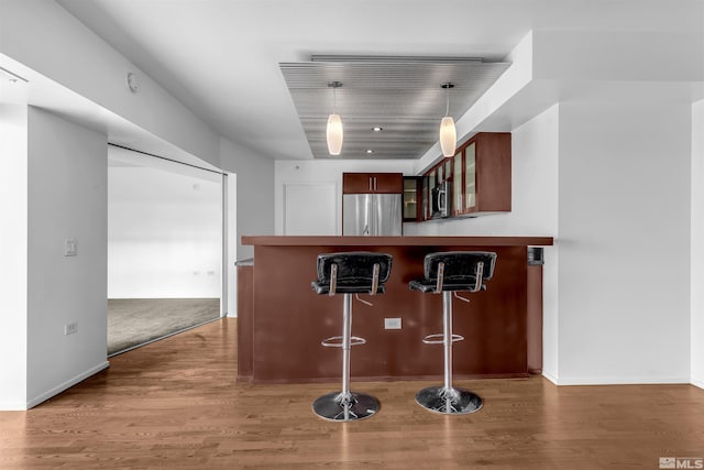 255 N Sierra St Unit 815, Reno, NV 89501 - kitchen featuring stainless steel appliances, a breakfast bar area, glass insert cabinets, wood finished floors, and a peninsula