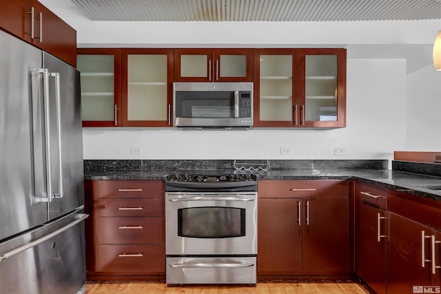 255 N Sierra St Unit 815, Reno, NV 89501 - kitchen with appliances with stainless steel finishes, light wood-style flooring, dark stone countertops, and glass insert cabinets