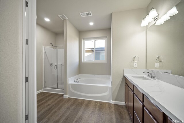 7117 Mustengo Dr, Reno, NV 89506 - bathroom featuring wood finished floors, a shower stall, a bath, vanity, and baseboards