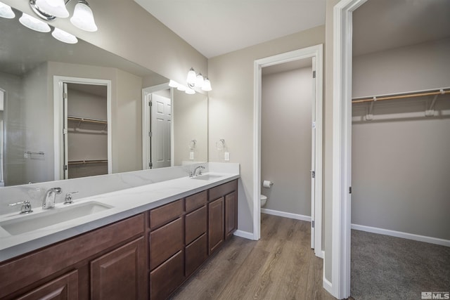 7117 Mustengo Dr, Reno, NV 89506 - full bathroom featuring toilet, wood finished floors, baseboards, double vanity, and a spacious closet