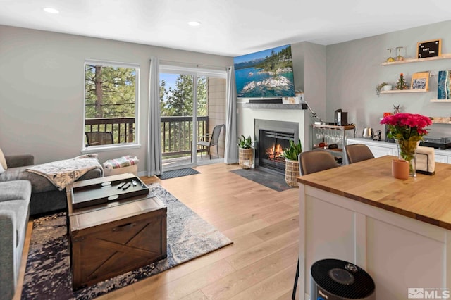 living area with a fireplace with flush hearth, light wood finished floors, and recessed lighting