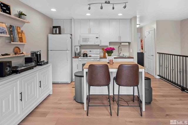kitchen featuring white appliances, a sink, light wood-style floors, a kitchen breakfast bar, and recessed lighting