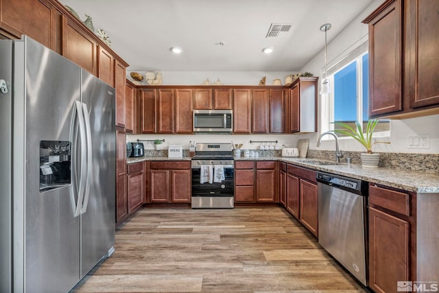 5030 Ronald Stephen Cir, Reno, NV 89503 - kitchen with stainless steel appliances, a sink, light stone counters, light wood finished floors, and pendant lighting