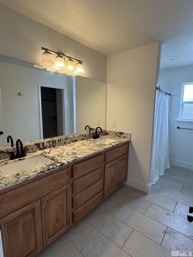794 Megan Way, Fallon, NV 89406 - bathroom with double vanity, a textured ceiling, baseboards, and tile patterned floors