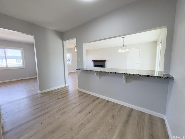 675 L St, Hawthorne, NV 89415 - kitchen featuring a kitchen bar, light wood-type flooring, light stone countertops, and a fireplace