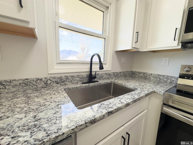 675 L St, Hawthorne, NV 89415 - kitchen with appliances with stainless steel finishes, a sink, white cabinetry, and light stone countertops