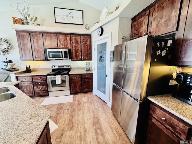 629 Ross St, Winnemucca, NV 89445 - kitchen featuring appliances with stainless steel finishes, light wood finished floors, lofted ceiling, dark brown cabinets, and a sink