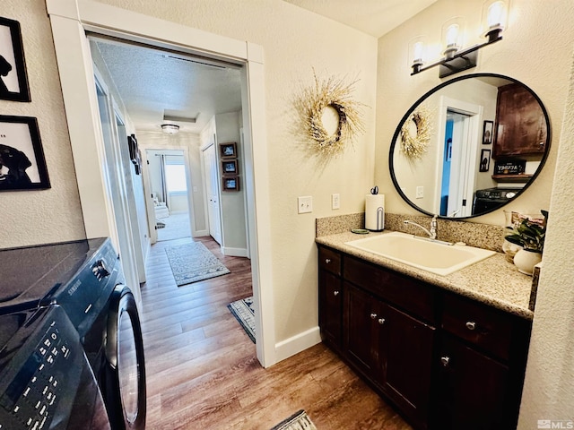 629 Ross St, Winnemucca, NV 89445 - bathroom with wood finished floors, washer / clothes dryer, vanity, baseboards, and a textured wall