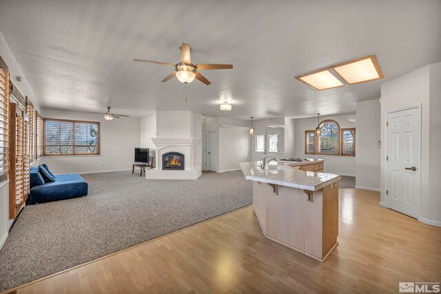 1568 Barker Ct, Gardnerville, NV 89410 - kitchen featuring tile counters, a glass covered fireplace, a breakfast bar, ceiling fan, and baseboards