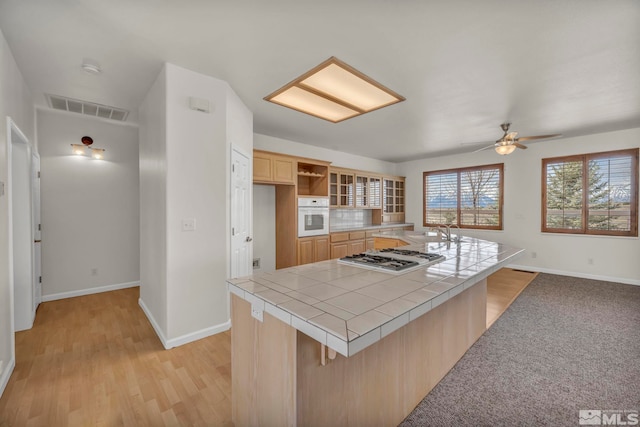 1568 Barker Ct, Gardnerville, NV 89410 - kitchen with gas cooktop, tile countertops, white oven, light brown cabinetry, and baseboards