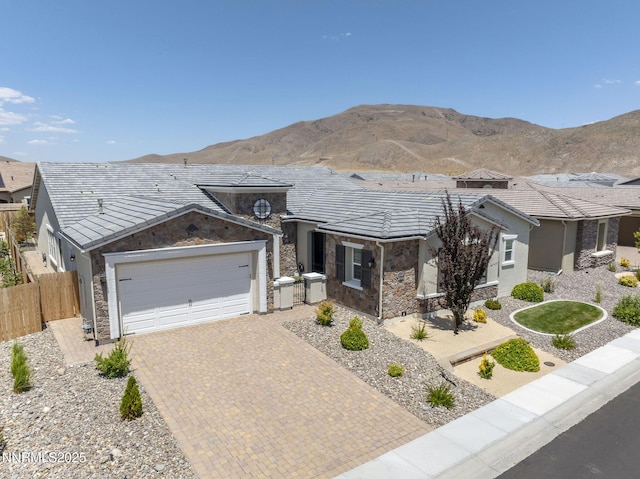 2313 Blushing Rock Dr, Reno, NV 89521 - view of front of house featuring stone siding, decorative driveway, a garage, stucco siding, and a mountain view