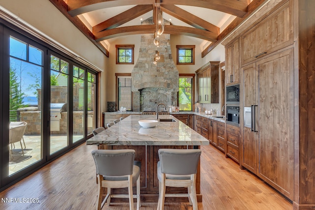 4250 N Lake Blvd, Carnelian Bay, CA 96140 - kitchen with high vaulted ceiling, beamed ceiling, an island with sink, light stone countertops, and brown cabinets