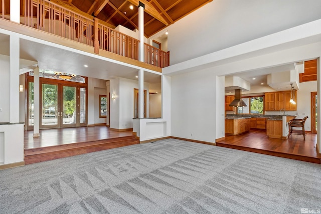 210 Sheridan Creek Ct, Gardnerville, NV 89460 - unfurnished living room featuring carpet flooring, healthy amount of natural light, baseboards, wooden ceiling with exposed beams, and wood finished floors