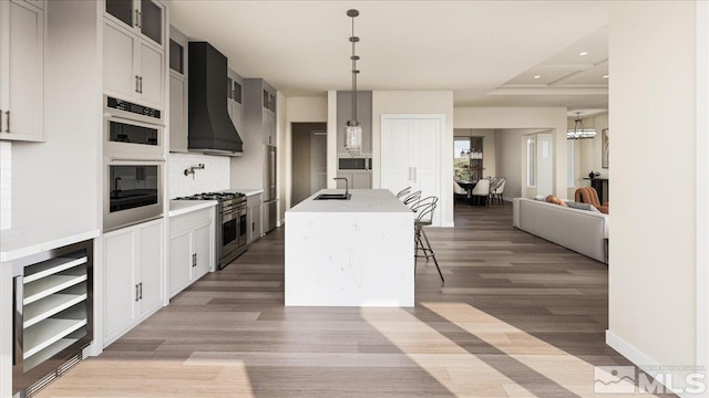1223 Golden Eagle Ct, Gardnerville, NV 89410 - kitchen with appliances with stainless steel finishes, premium range hood, light wood-type flooring, a center island with sink, and recessed lighting