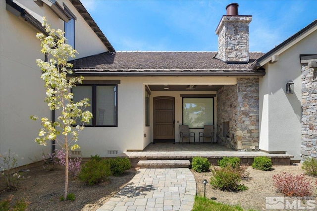 20765 Parc Foret Dr, Reno, NV 89511 - view of exterior entry with a chimney, stucco siding, and a porch