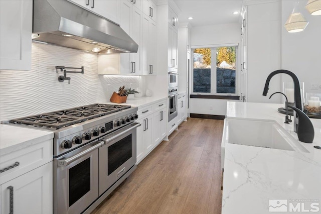 20765 Parc Foret Dr, Reno, NV 89511 - kitchen featuring appliances with stainless steel finishes, under cabinet range hood, a sink, white cabinetry, and tasteful backsplash