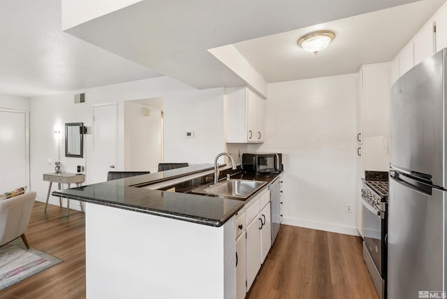 2445 Sycamore Glen Dr Unit 6, Sparks, NV 89434 - kitchen featuring stainless steel appliances, a sink, a peninsula, dark countertops, and wood finished floors