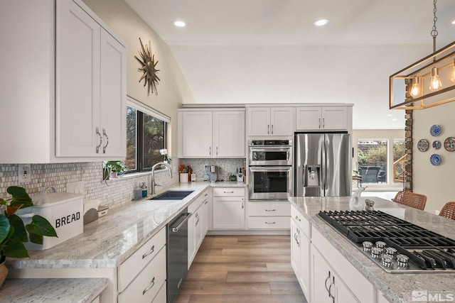 4400 Bridle Way, Reno, NV 89519 - kitchen featuring appliances with stainless steel finishes, a sink, tasteful backsplash, hanging light fixtures, and light wood-type flooring