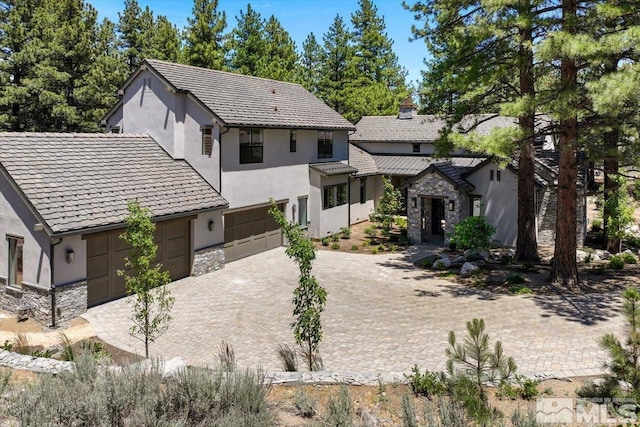 5192 Bordeaux Dr, Reno, NV 89511 - view of front facade with stone siding, stucco siding, a garage, driveway, and a chimney