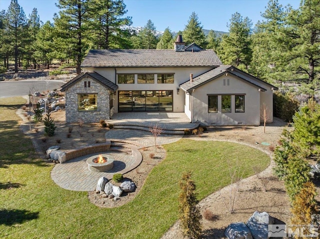 5192 Bordeaux Dr, Reno, NV 89511 - rear view of property featuring stucco siding, an outdoor fire pit, a lawn, and a patio area