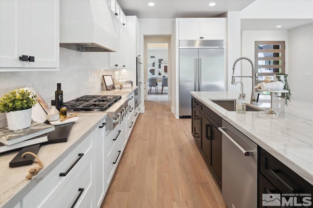 5192 Bordeaux Dr, Reno, NV 89511 - kitchen with stainless steel appliances, custom exhaust hood, a sink, white cabinetry, and light stone countertops
