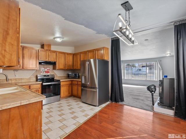 1248 Lindsay Ln, Carson City, NV 89706 - kitchen featuring appliances with stainless steel finishes, a sink, light countertops, under cabinet range hood, and brown cabinetry