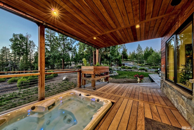 deck featuring an outdoor hot tub and view of wooded area